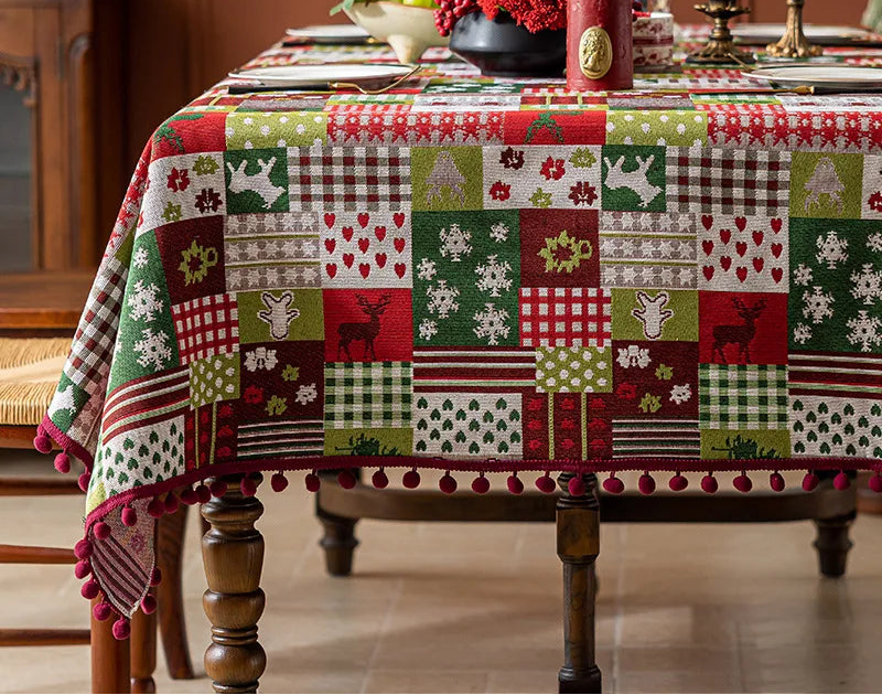 Nappe de table en patchwork colorée avec motifs de Noël, décorations florales et bougeoirs sur une table en bois.