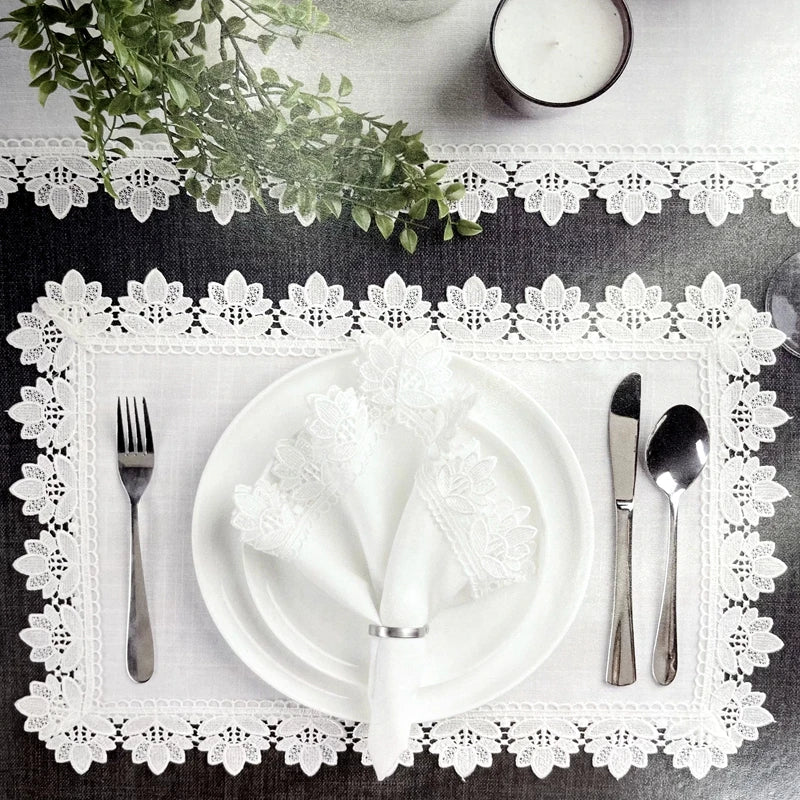 Table de service élégante avec nappe, assiettes blanches, couverts en argent et décoration florale.