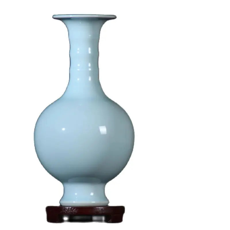 Vase en céramique de couleur bleu pâle sur un support en bois.