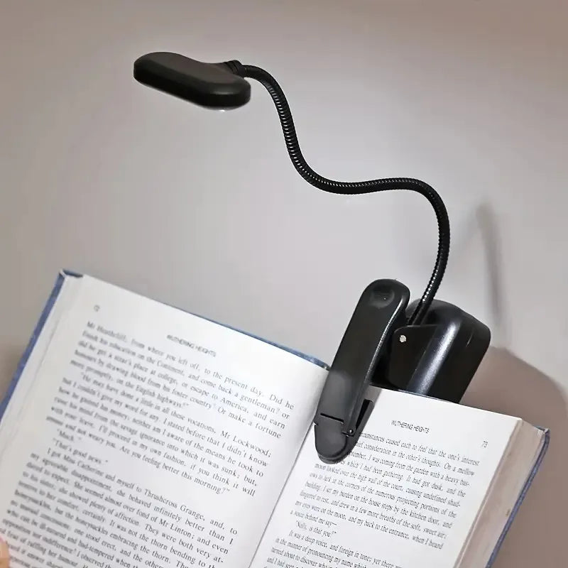 Lampe de chevet pince LED en couleur noire éclairant une table de nuit