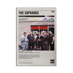 Le visuel présente l'affiche de la série télévisée "The Sopranos" créée par David Chase, montrant un groupe d'hommes debout devant un magasin de quartier en 1999.