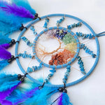 Un capteur de rêves aux accents ethniques, composé d'un cercle de perles de turquoise, de pierres semi-précieuses colorées et de plumes violettes et bleues.