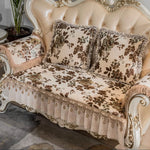 Un canapé à l'ancienne orné de motifs floraux dans des tons de brun, avec des coussins assortis et une frange élégante, placé dans un intérieur chic et sophistiqué.