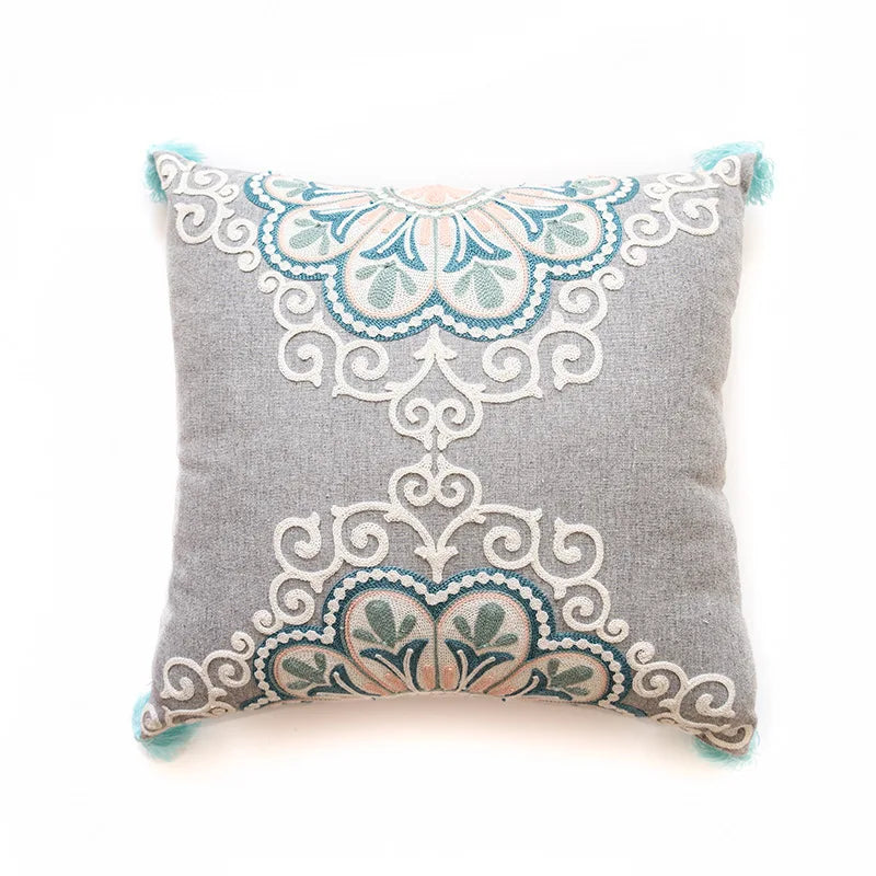 Coussin décoratif gris avec des ornements floraux et motifs élégants.