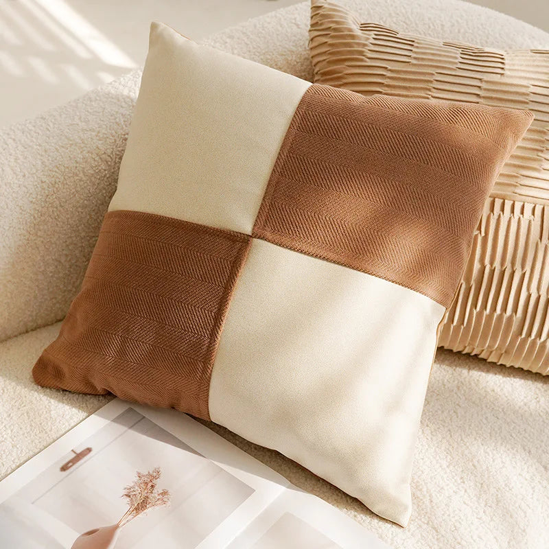 Coussin décoratif beige et brun avec des motifs géométriques, posé sur un lit moelleux avec d'autres oreillers et accessoires de décoration.