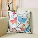 Coussin décoratif orné de papillons multicolores brodés sur un fond blanc, créant une atmosphère douce et apaisante.