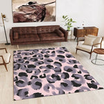 Un tapis moderne et coloré avec un motif de léopard abstrait dans des tons roses et gris, placé dans un intérieur contemporain avec un canapé en cuir marron et des meubles en bois.