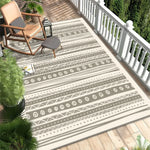L'image montre un patio extérieur avec des meubles de jardin, un tapis à motifs graphiques et des plantes tropicales, créant une atmosphère décontractée et chaleureuse.