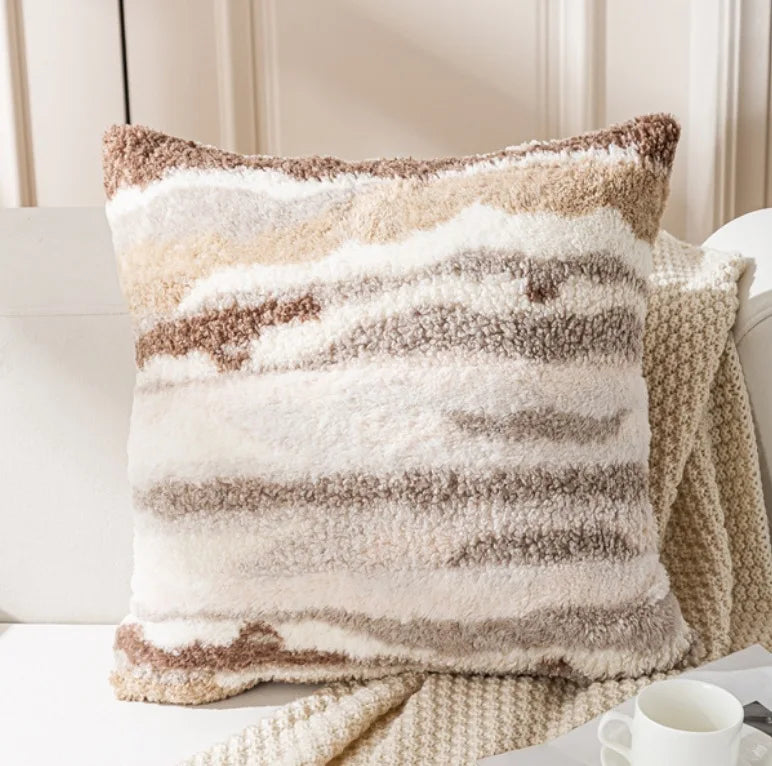 Ce coussin douillet présente un motif de lignes horizontales beige et blanches, créant une texture moelleuse et confortable.