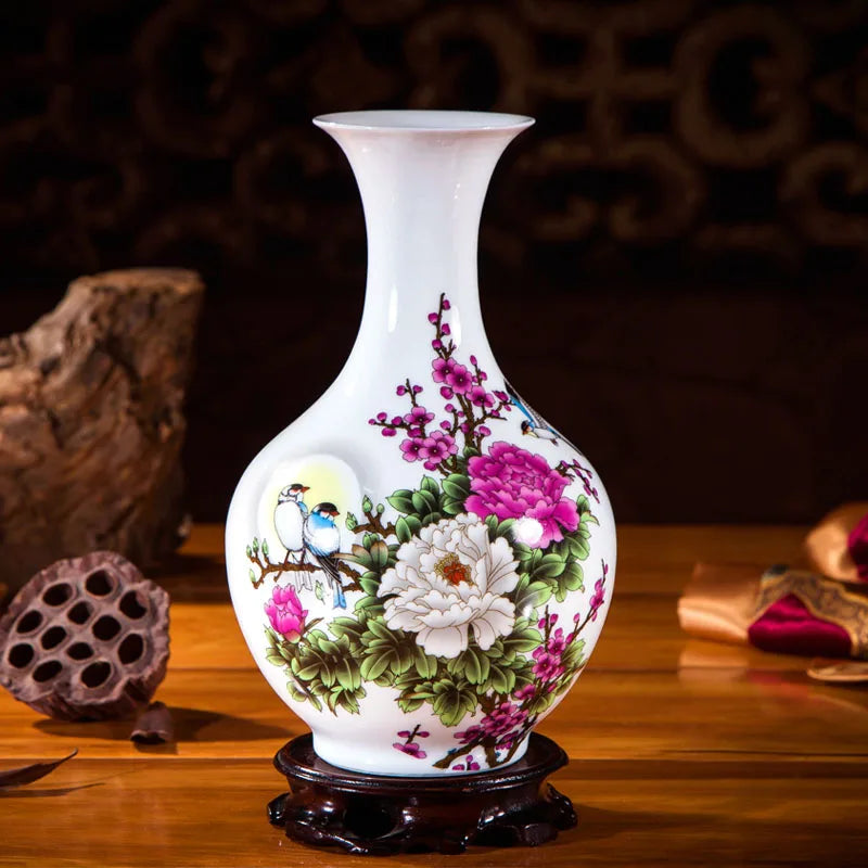Vase décoratif en porcelaine blanche avec des fleurs de pivoine et d'autres fleurs asiatiques sur un piédestal en bois sombre.