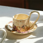 Une tasse de porcelaine vintage au motif floral whimsique, accompagnée de sa soucoupe assortie, évoquant une atmosphère chaleureuse et rêveuse.