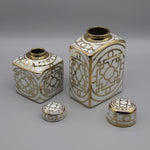 Ensemble de boîtes décoratives en porcelaine blanche et dorée avec des motifs géométriques élégants.
