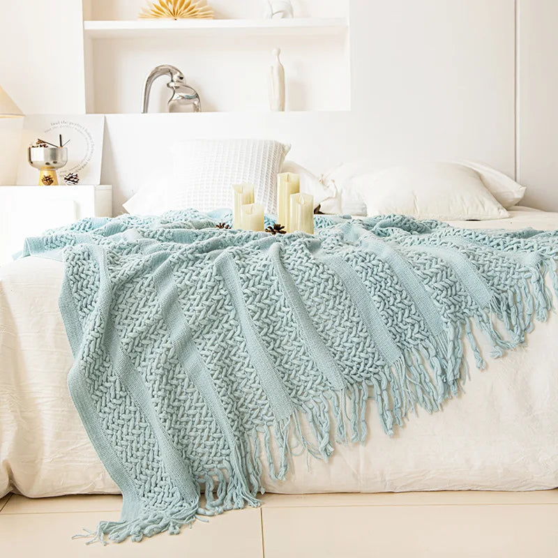 Couverture douillette avec une texture tricotée à franges sur un lit.
