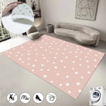 Un tapis rose à motifs d'étoiles blanches, agrémenté de coussins gris, d'une lampe suspendue et d'un canapé confortable, créant une ambiance chaleureuse et apaisante dans cette pièce.