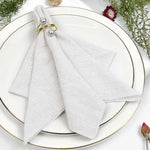 Serviettes blanches avec anneaux dorés sur une assiette blanche décorée de fleurs fraîches.