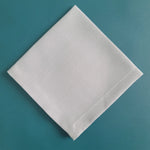 Une dalle blanche rectangulaire repose sur un fond turquoise uniforme.
