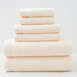 Pile de serviettes de bain moelleuses et blanches, empilées sur un fond uni.