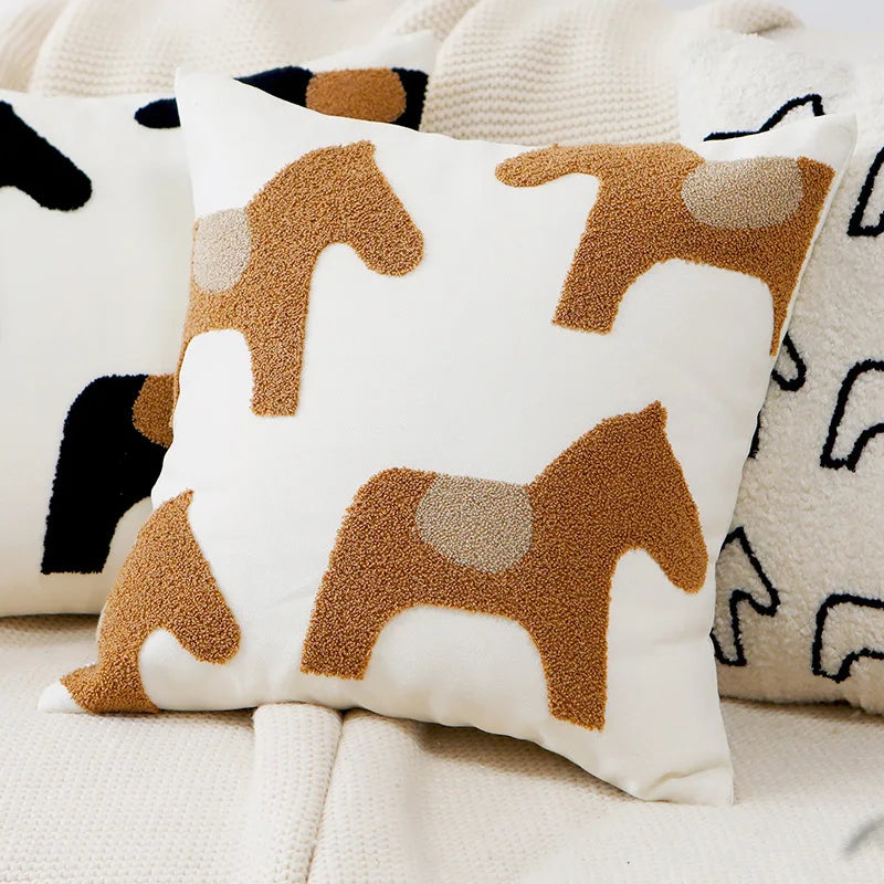 Coussin décoratif avec des motifs de chevaux en couleurs neutres, créant une ambiance douce et cosy.