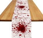 Un chemin de table décoré de taches et d'éclaboussures de couleur rouge sang, créant une ambiance sombre et inquiétante sur la surface en bois.