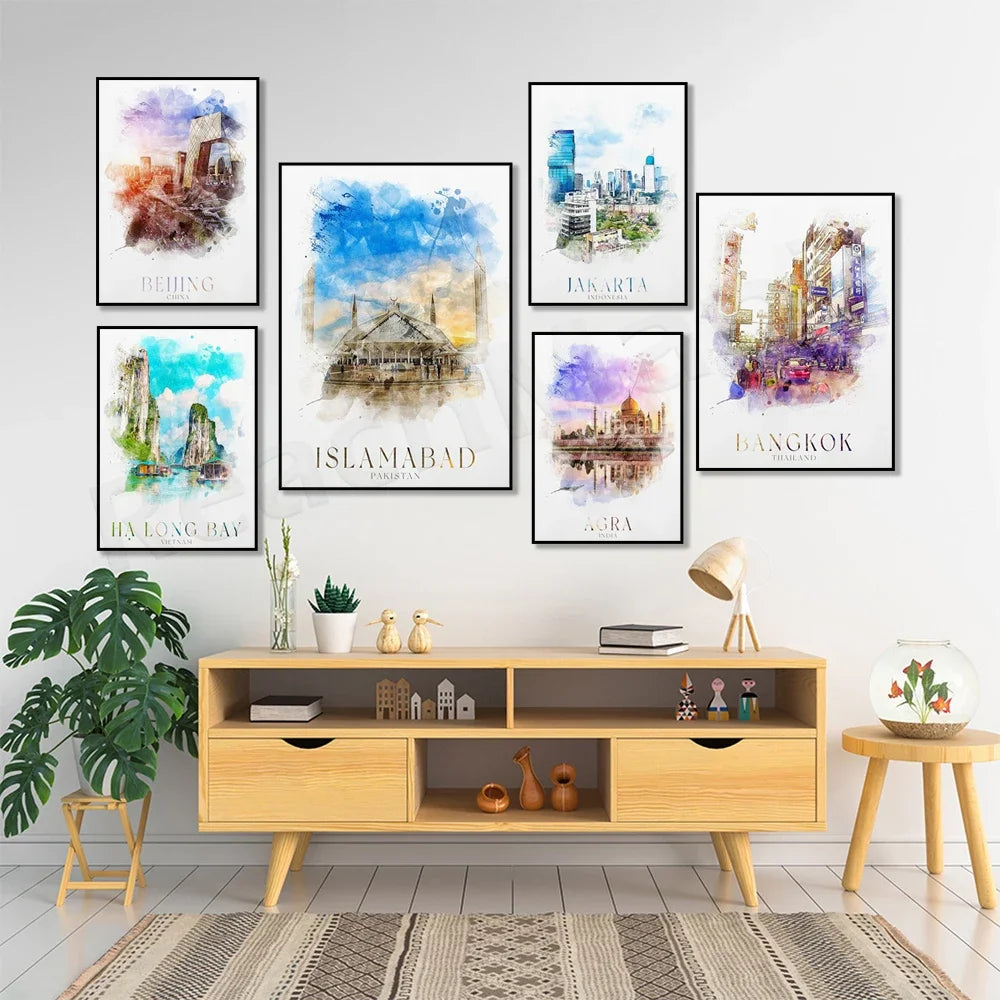 Cette image présente une collection de toiles murales représentant diverses villes et paysages, encadrées et disposées sur un mur blanc, accompagnées d'un meuble de rangement en bois clair, de plantes vertes et d'autres éléments décoratifs, créant une atmosphère chaleureuse et voyageuse dans cette pièce.