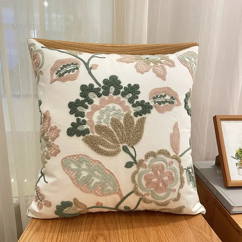 Coussin décoratif à motifs floraux colorés et brodés, créant une ambiance chaleureuse et élégante dans l'espace.