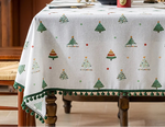 Une nappe de table de Noël ornée de motifs d'arbres de Noël et de pompons verts, créant une ambiance festive et chaleureuse pour les repas de fête.