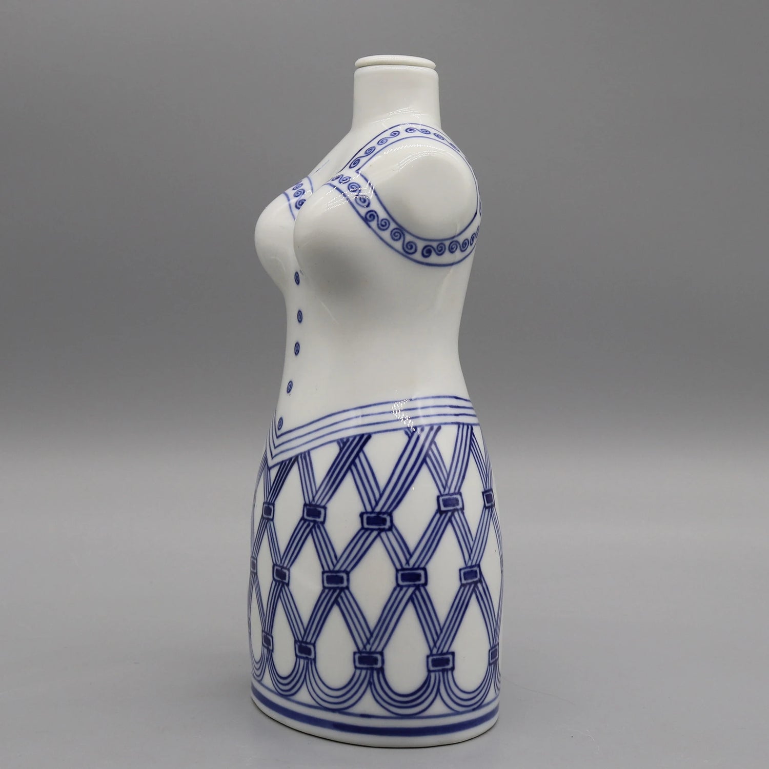 Photographie d'un vase de couleur blanche avec un motif bleu en forme de spirale et de rayures entrecroisées.