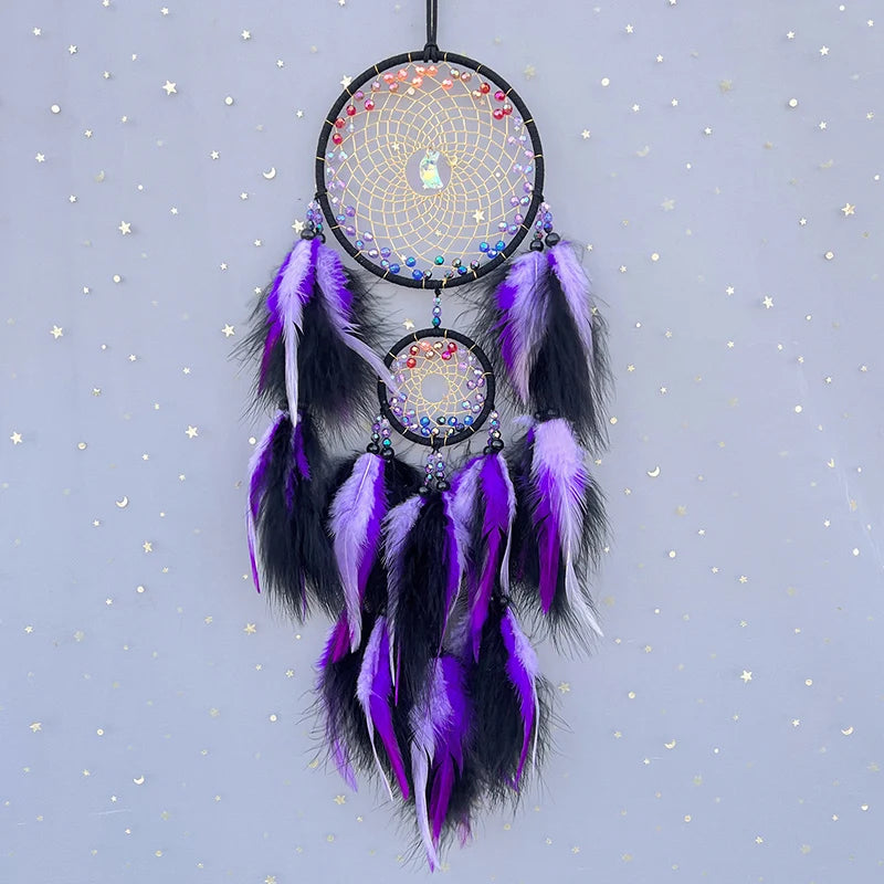 Un capteur de rêves décoratif violet et noir, fait main avec des plumes et des perles colorées disposées dans un motif de toile d'araignée, suspendu devant un ciel étoilé.