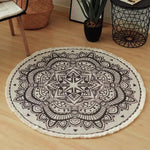 Tapis rond décoratif avec un motif mandala ornemental noir et blanc, posé sur un plancher de bois clair dans un intérieur moderne.