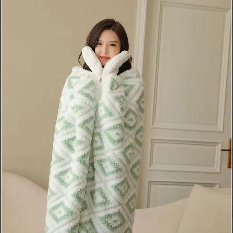 Un modèle portant un plaid moelleux et douillet de couleur blanche et verte, s'enveloppant dans l'épaisseur du tissu pour se réchauffer dans un intérieur confortable.