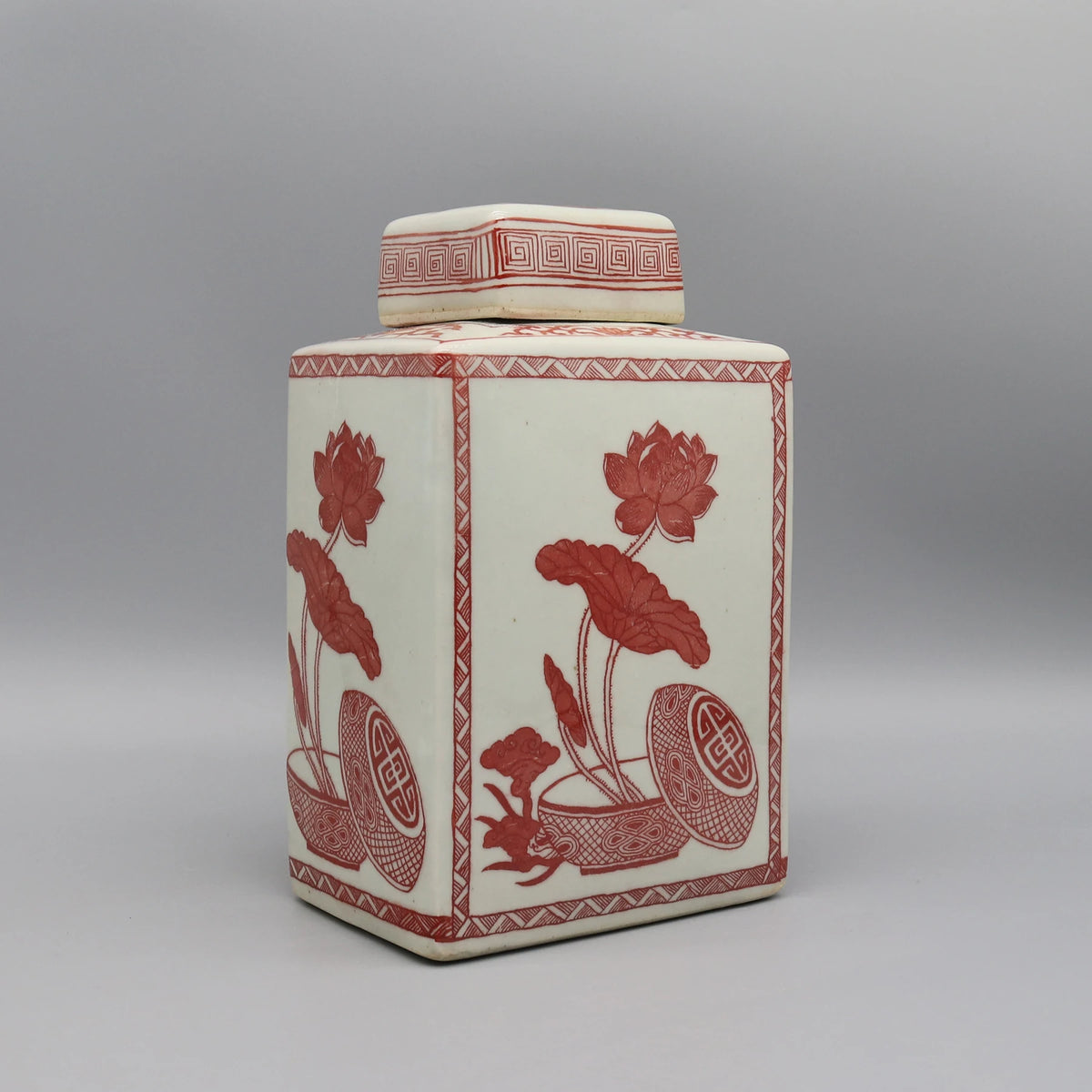 Pot décoratif en céramique blanc avec motifs floraux rouges et motifs géométriques.