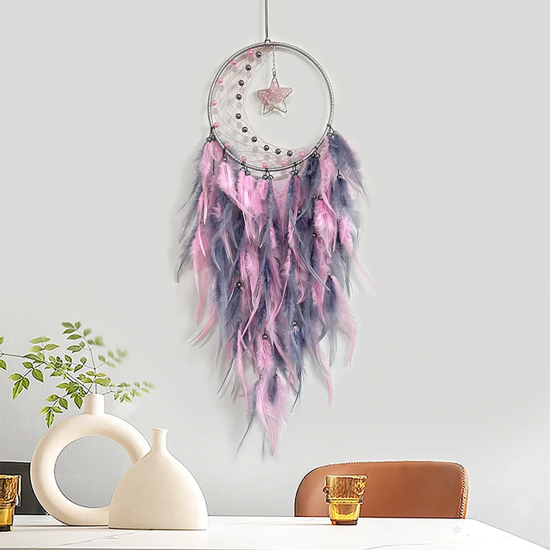 Capteur de rêves suspendu avec des plumes roses et grises, décoré d'une étoile brillante.
