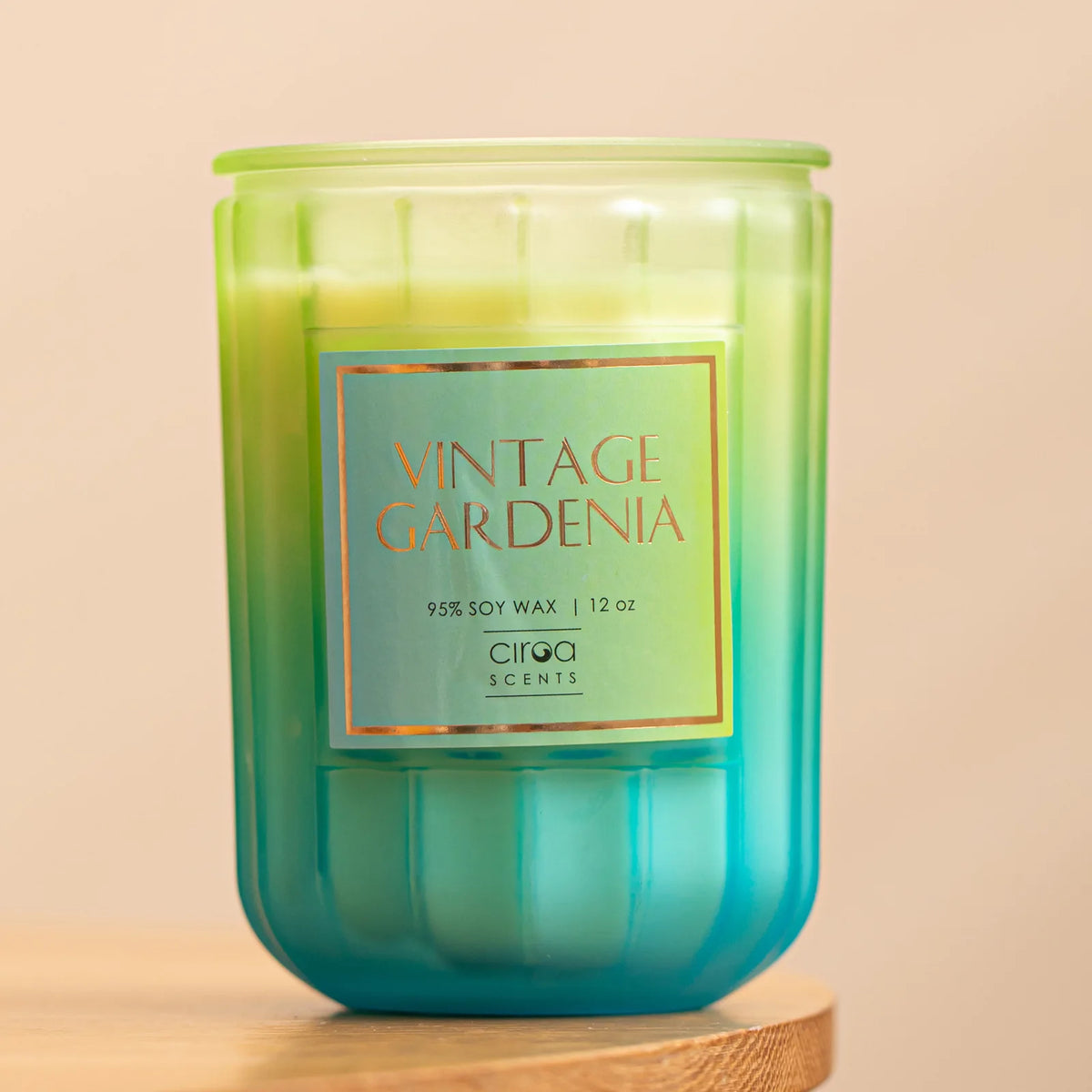 Bougie parfumée verte intitulée "Vintage Gardenia" de la marque Circa Scents, avec un contenant en verre et une étiquette orange indiquant la composition en cire de soja à 95%.