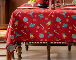 Une magnifique nappe de table rouge ornée de motifs de Noël colorés, comme des boules, des cloches et des flocons de neige, créant une ambiance festive et chaleureuse pour les fêtes.