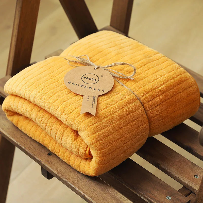Un épais plaid jaune moutarde, douillettement enroulé sur un châssis en bois, décoré d'une étiquette élégante avec le mot "Webpy" écrit dessus.