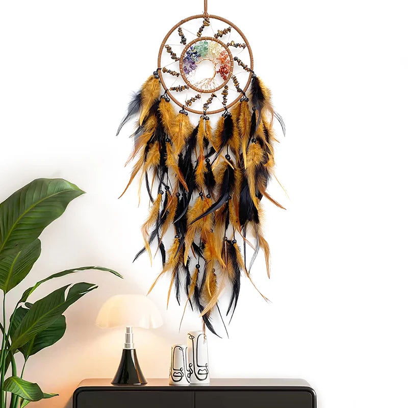 L'image représente un capteur de rêves décoratif orné de plumes jaunes et noires, suspendu à un crochet en forme de soleil entouré de pierres colorées.
