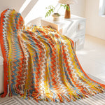 Une couverture multicolore aux motifs géométriques audacieux et éclatants, ornée de franges, confère une ambiance chaleureuse et accueillante à cette pièce de décoration.