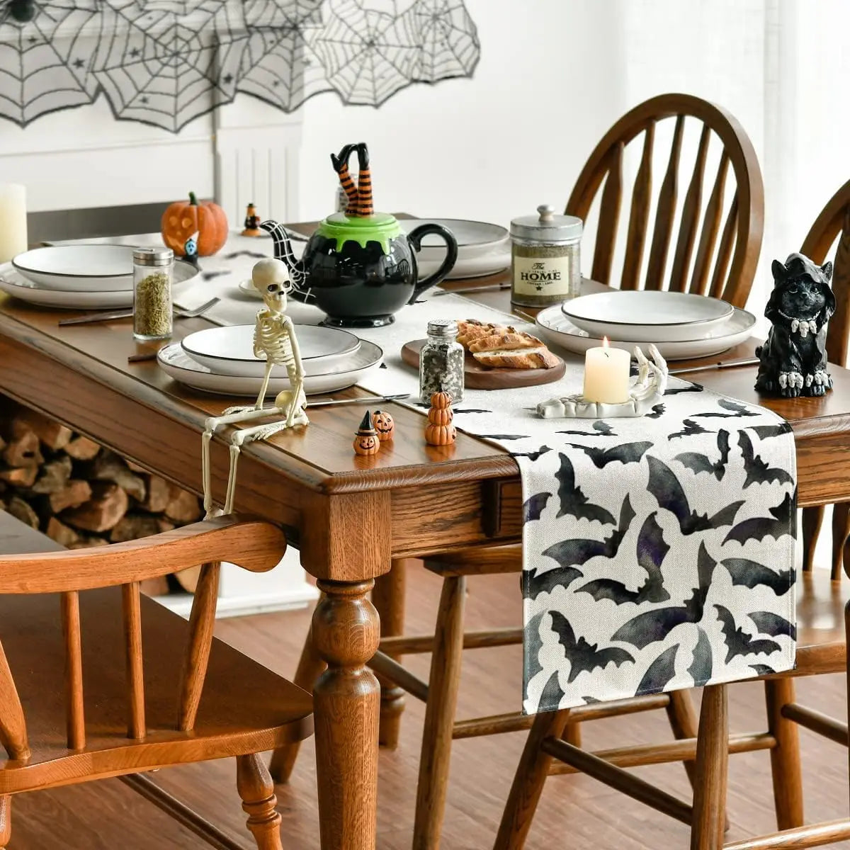 Une table de cuisine décorée de motifs d'Halloween, avec des plats, des bougies et des figurines thématiques.