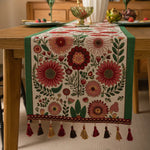 Cette image représente un magnifique chemin de table orné de fleurs aux couleurs riches et variées, créant une atmosphère chaleureuse et accueillante pour une table dressée avec soin.