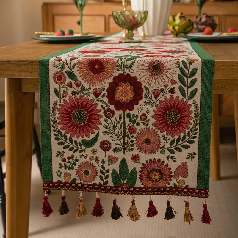 Cette image représente un magnifique chemin de table orné de fleurs aux couleurs riches et variées, créant une atmosphère chaleureuse et accueillante pour une table dressée avec soin.