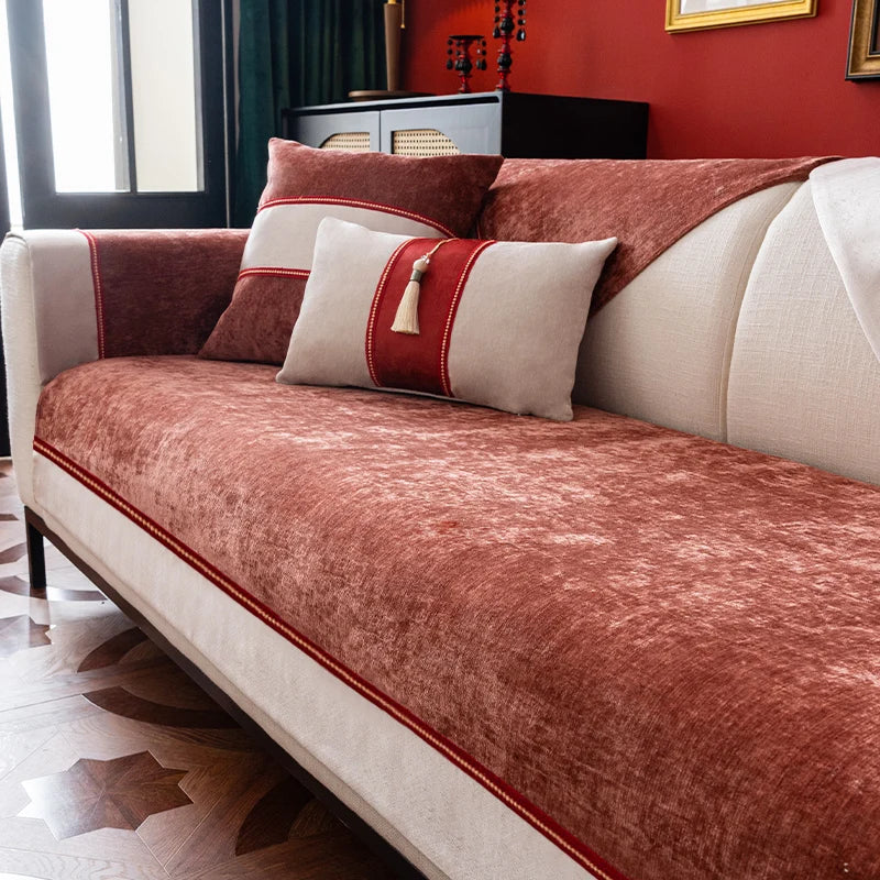 Un canapé moelleux et élégant aux tons chauds de rouges et de beiges, orné de coussins décoratifs, offrant un confort et une atmosphère cocooning dans cette pièce.