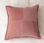 Un coussin rose en velours côtelé, avec un motif géométrique contrasté, offrant une touche de douceur et d'élégance à l'espace.