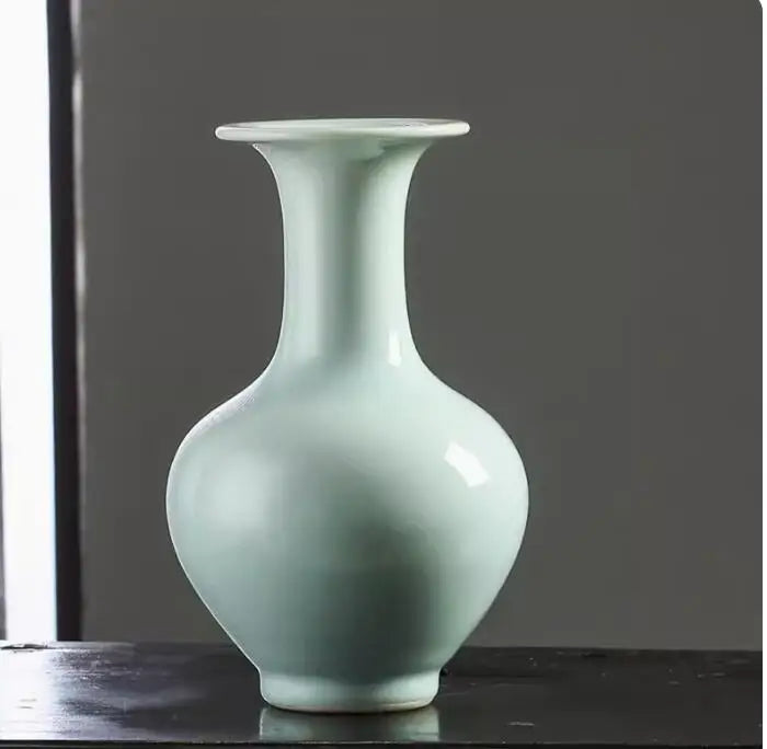 Vase en céramique de couleur vert pâle avec une forme élégante et épurée, posé sur une surface sombre.