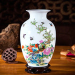 Vase en céramique blanc décoré de fleurs et d'oiseaux colorés dans un style traditionnel chinois, placé sur un fond sombre avec un support en bois.