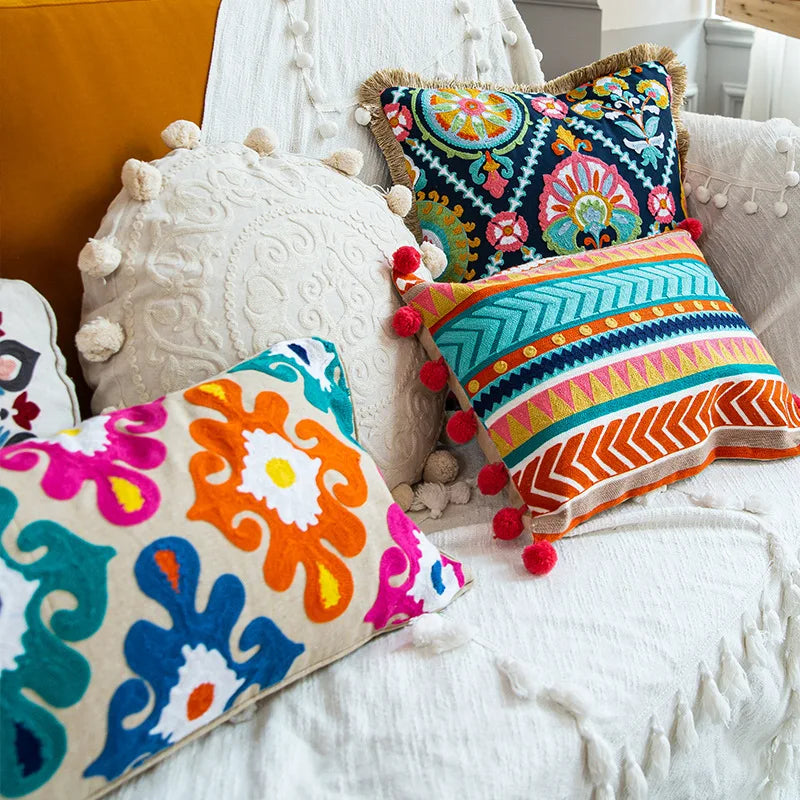 Coussin décoratif coloré avec des motifs ethniques et des pompons, offrant une touche de style bohème à l'environnement.