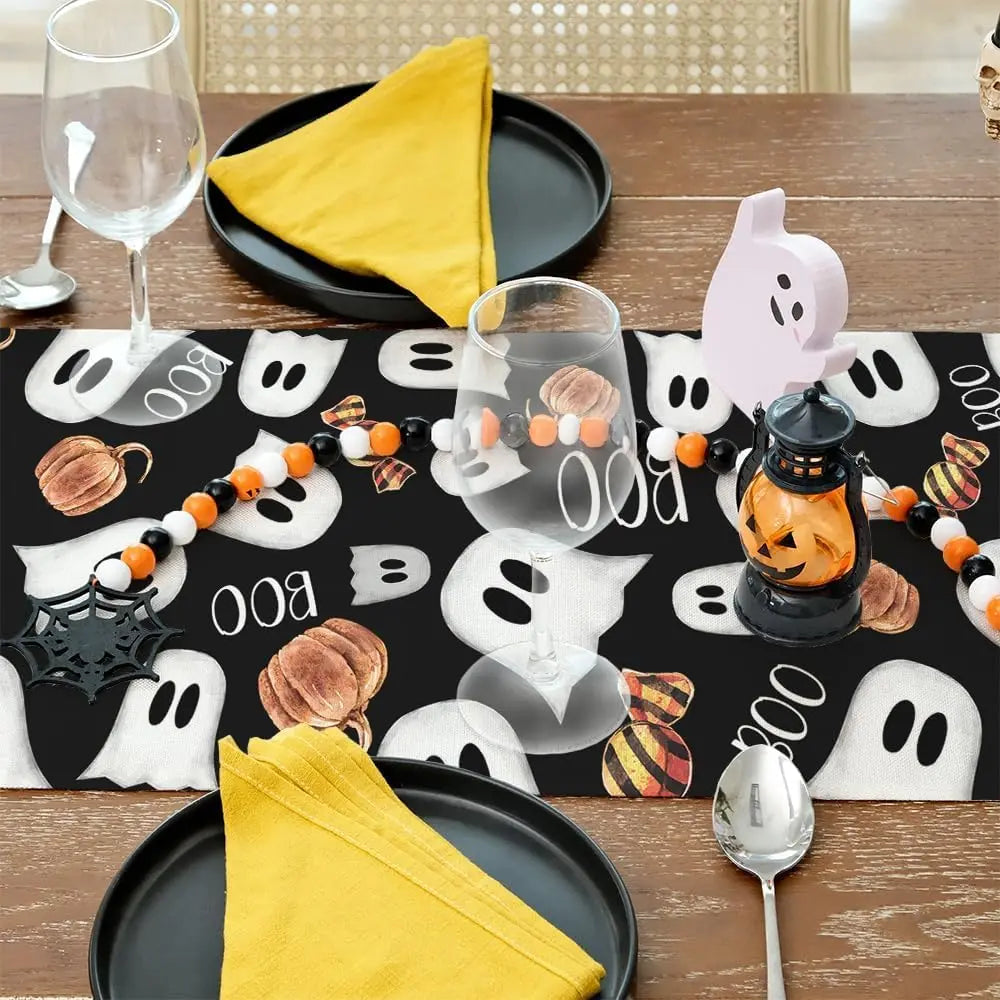 Une table décorée pour une célébration d'Halloween, avec des fantômes blancs, des citrouilles, des bougies et des décorations noires et jaunes.