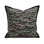 Coussin décoratif avec des motifs géométriques et abstraits dans des tons de vert, beige et noir, créant un design élégant et dynamique.