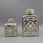 Ces deux récipients décorés de motifs géométriques noirs et or sur un fond blanc apportent une touche de design graphique élégant.