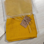 Serviettes en lin pur emballées et étiquetées, dans une couleur jaune moutarde vive.