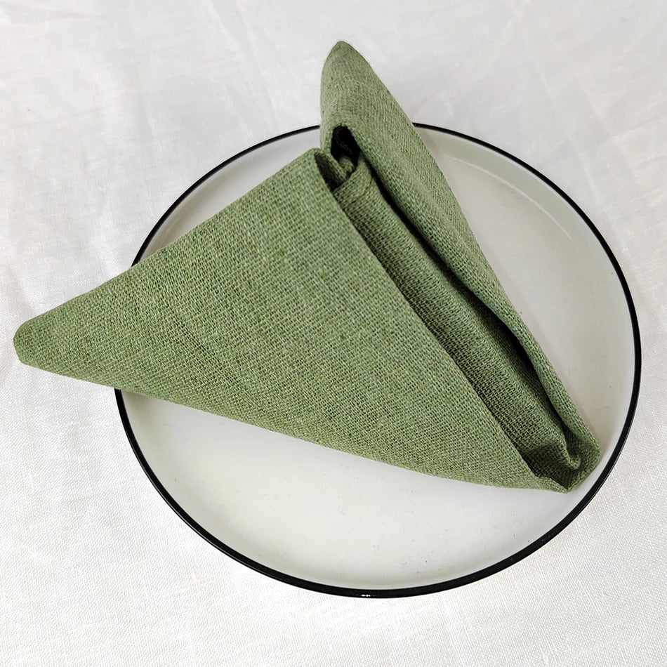 Une serviette de table verte pliée sur une assiette sombre.